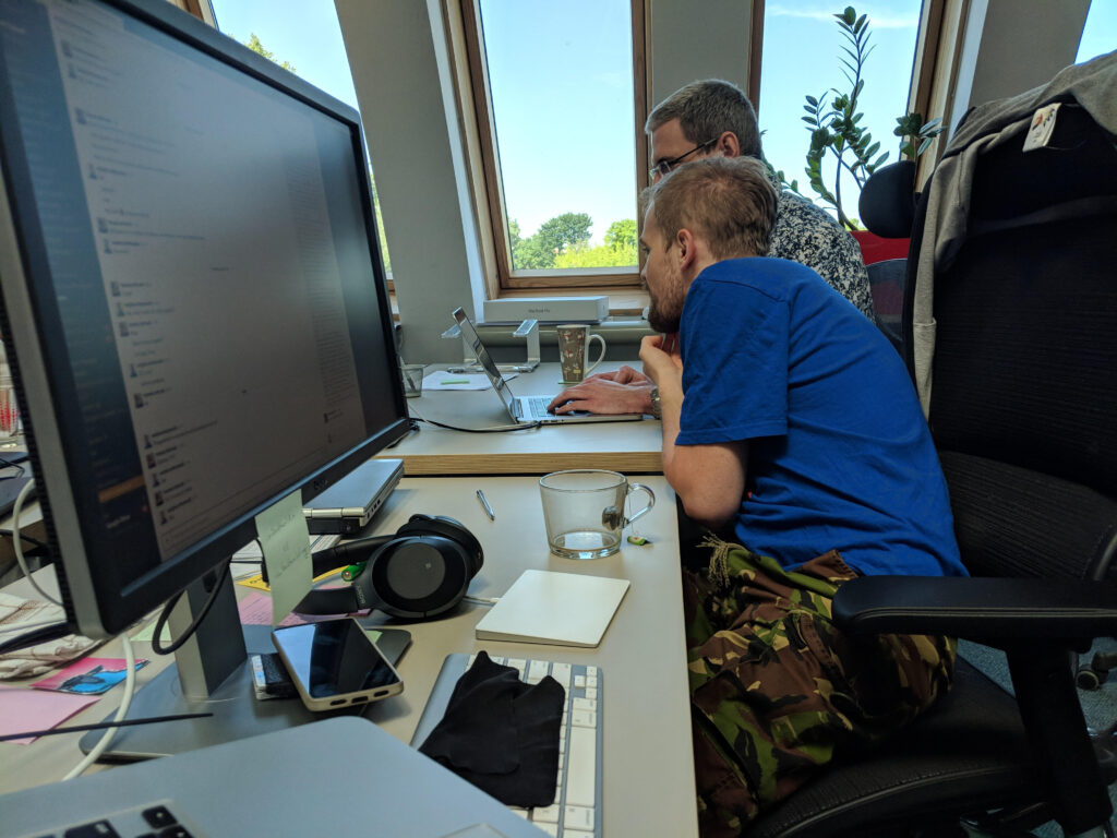 A professional looking over at his colleague’s laptop.