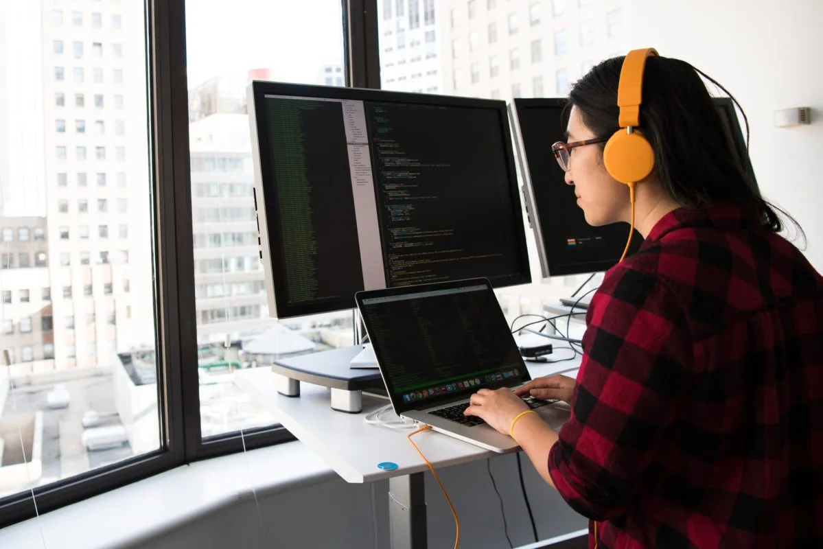 Women working on a laptop with two additional monitors